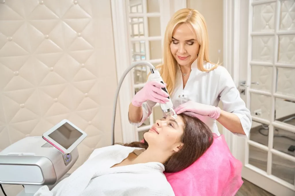 Professional performing RF Microneedling on a client’s forehead in Needham, MA